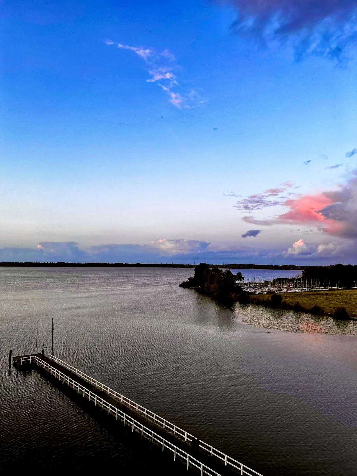 Sanfter Sonnenuntergang mit farbigen Wolken über dem See und Hafen