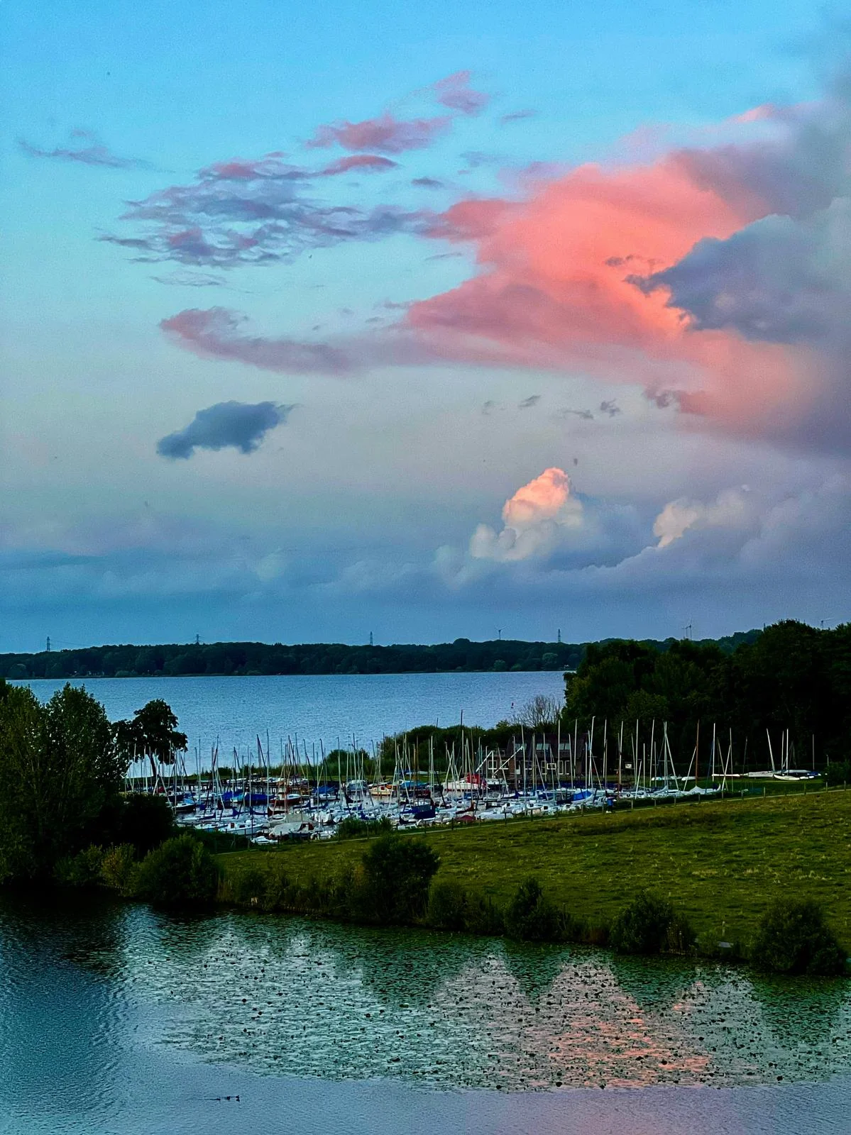 Intensiv pink leuchtende Wolken bei Sonnenuntergang über dem Hafen
