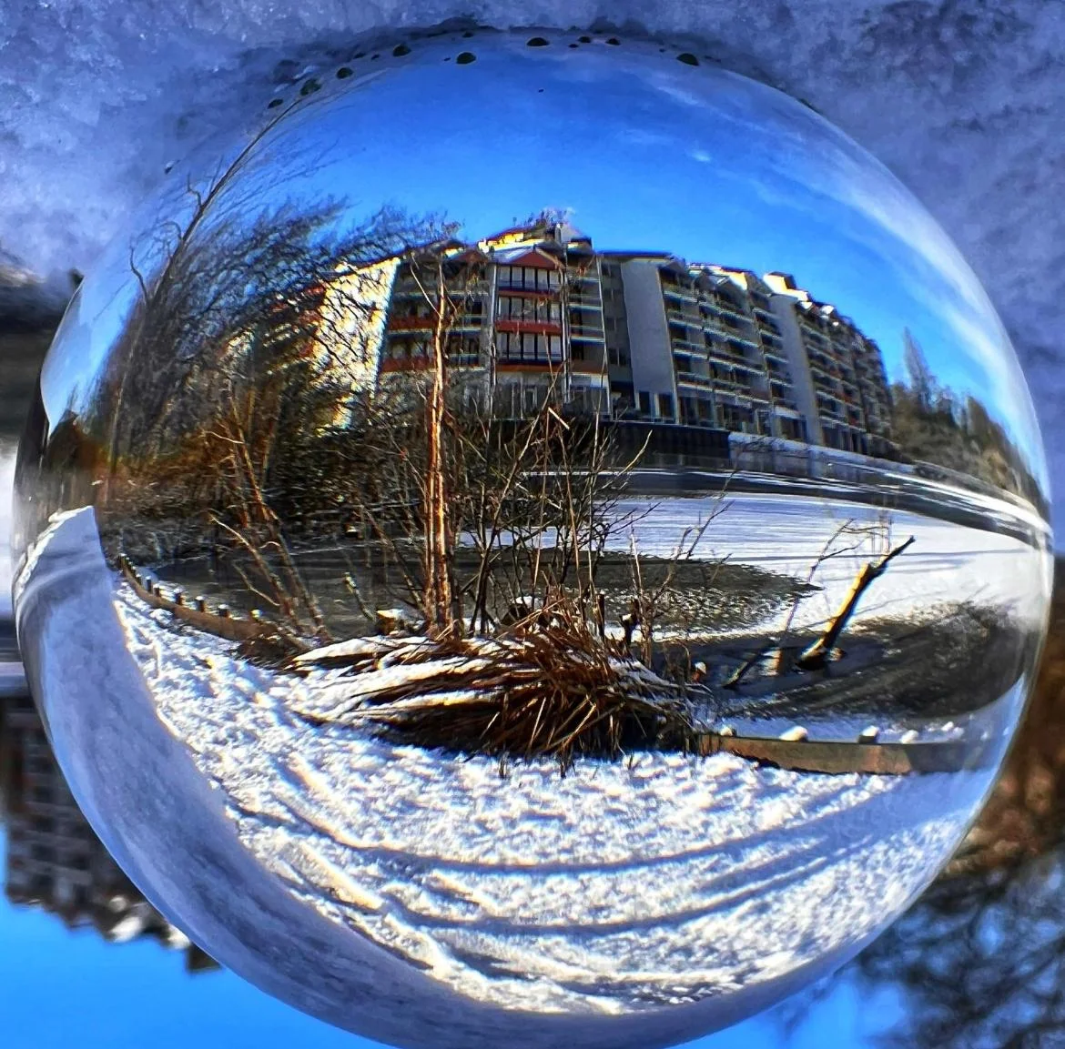 Glaskugel-Fotografie: Eine weite Winterlandschaft mit Bäumen am gefrorenen See