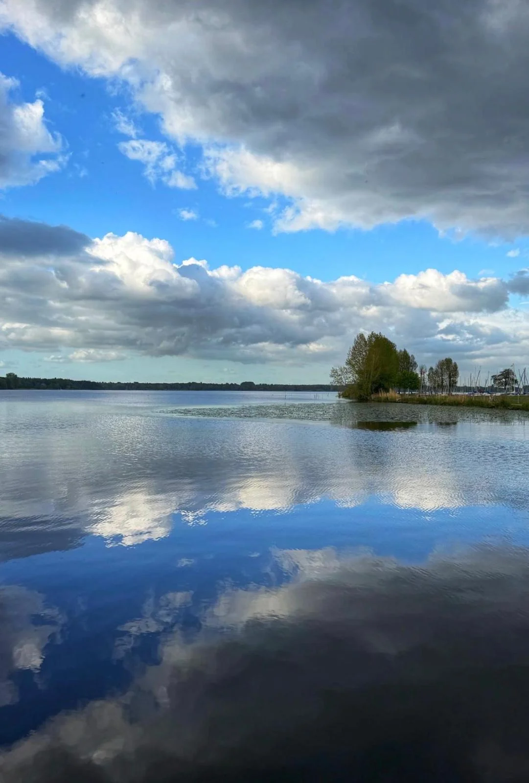 Wunderschöne Wolkenformationen spiegeln sich im ruhigen Wasser des Sees