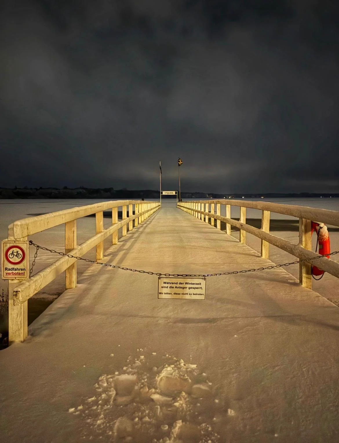 Verschneiter Steg (Eyhausen) in den See bei Nacht mit Sperrschildern