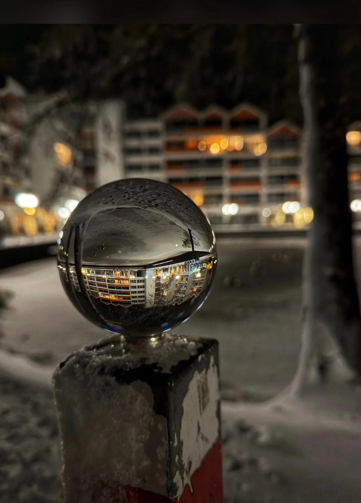 Glaskugel-Fotografie: Die erleuchtete Wohnanlage bei Nacht in der Kugel gefangen