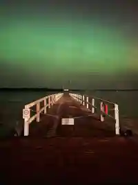Der Steg in Eyhausen führt in den See unter leuchtend grünen Polarlichtern