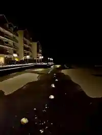 Die hell erleuchtete Wohnanlage an der winterlichen Seeseite bei Nacht (zugefroren)