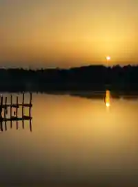 Goldener Sonnenuntergang über dem ruhigen See mit Holzsteg