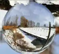 Glaskugel-Fotografie: Spiegelung der verschneiten Wohnanlage am Ufer