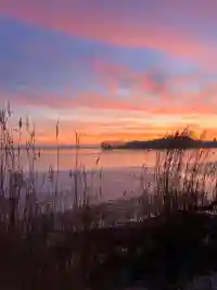 Romantischer Sonnenuntergang mit pinken Wolken über dem zugefrorenen See